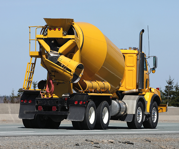 Yellow industrial cement truck driving down a concrete highway