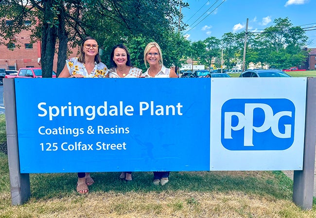 Maria Lamorey, a PPG employee within our Industrial Coatings business, behind the PPG Springdale plant entry banner with her colleagues