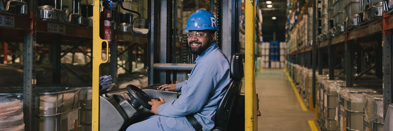 Worker in warehouse driving forklift truck