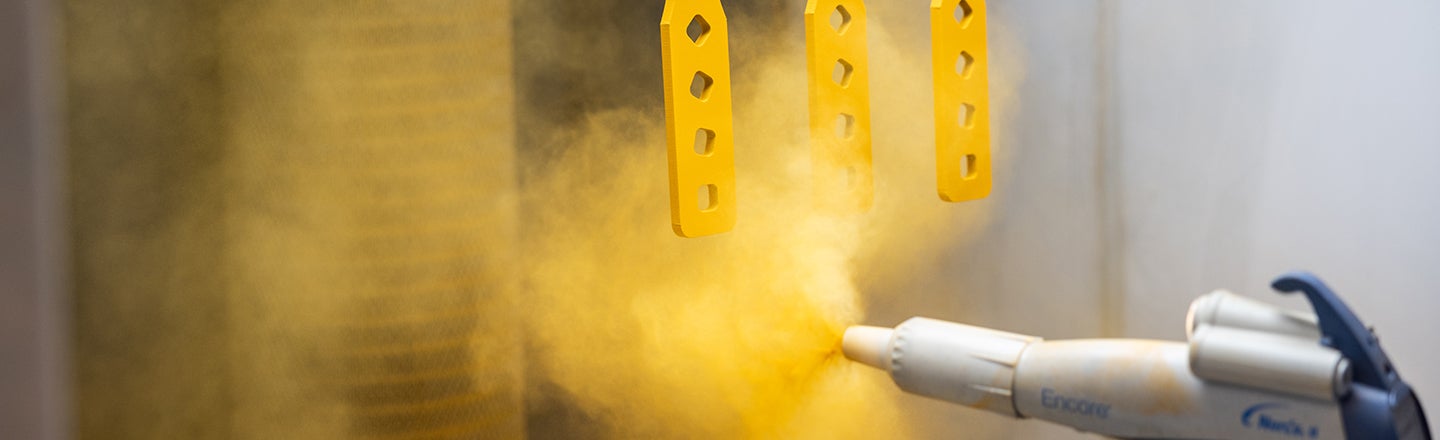 Spray gun being used to spray objects with yellow paint