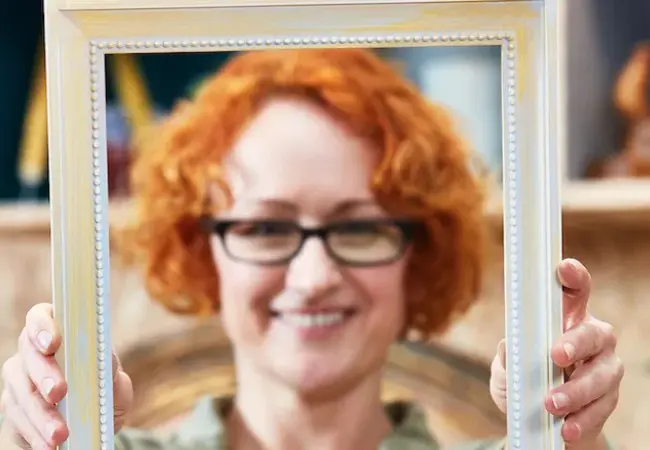 Usmívající se žena s rudými vlasy a brýlemi