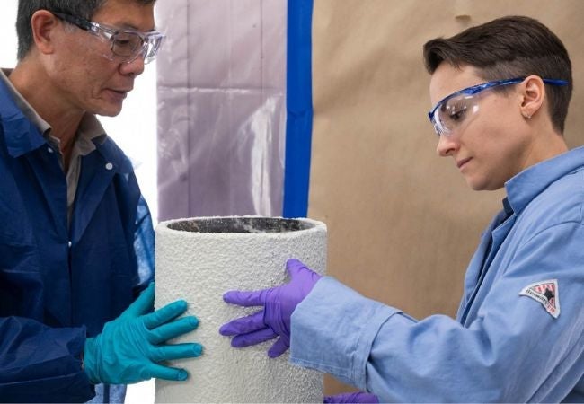 Two employees holding cylinder.