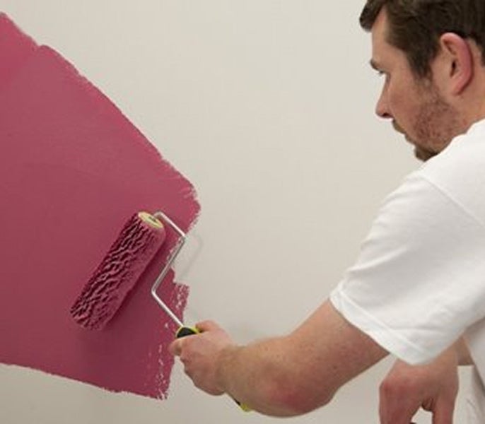 A man painting a wall with a paint roller