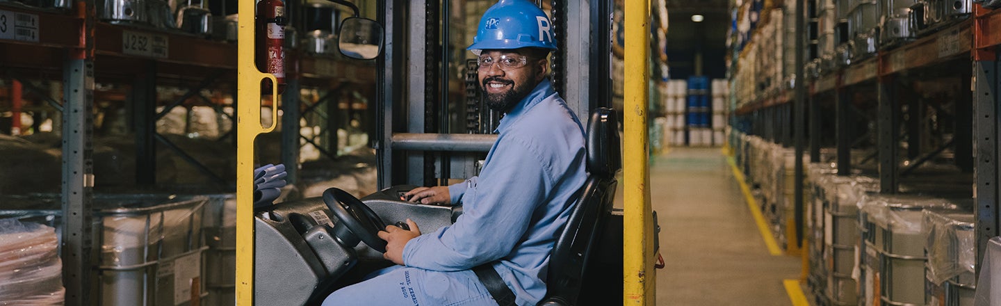 Worker in warehouse driving forklift truck