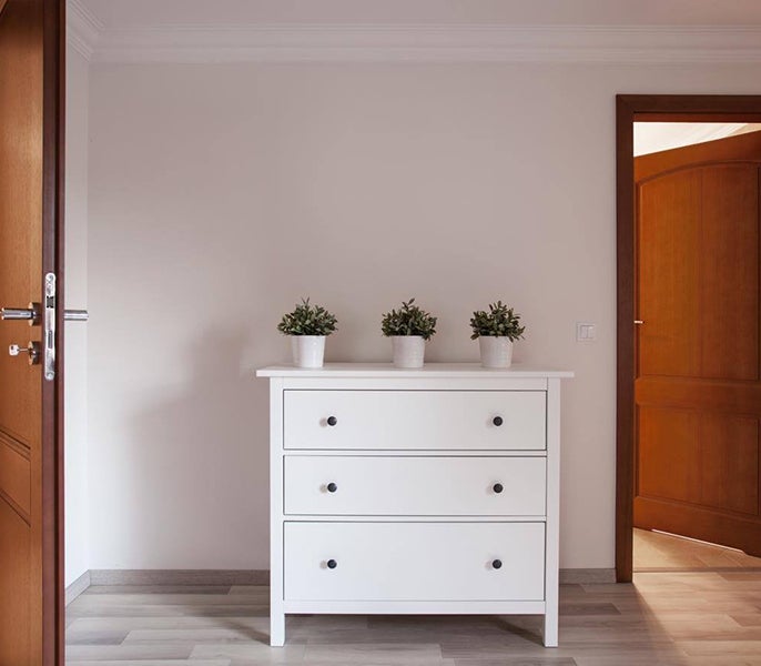 A white dresser with potted plants on top