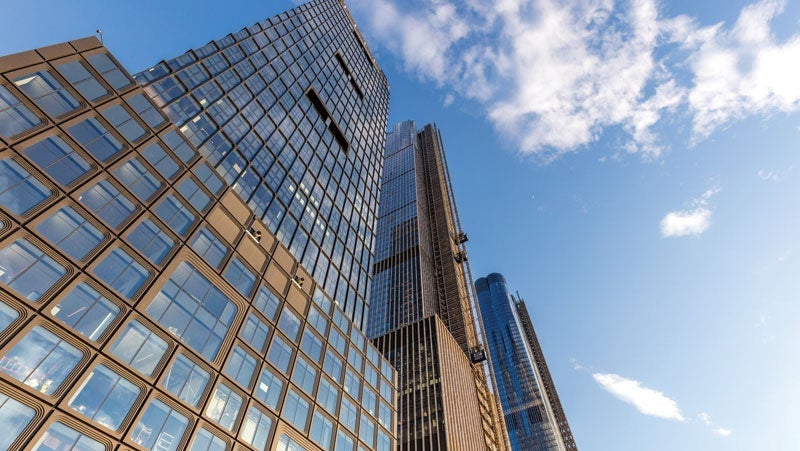 Low angle view of modern glass skyscrapers against a clear blue sky with fluffy clouds