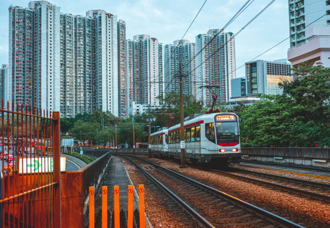 Light rail car body with red accents and city behind