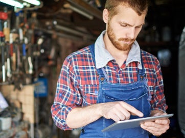 A man in overalls using a tablet