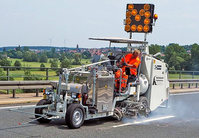 A person opreating a road-marking equipment, applying Thermodrop, a thermoplastic marking material, to a road