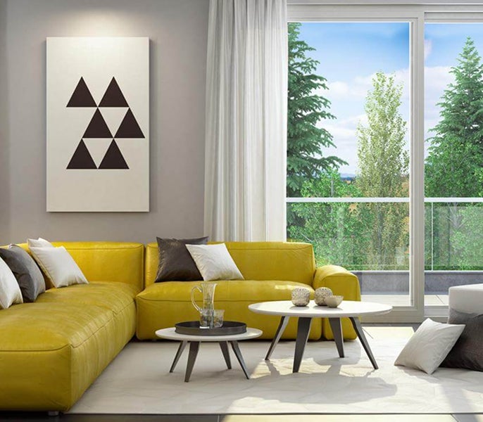 A living room with yellow couches and a painting