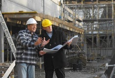 Een man met een helm die een blauwdruk vasthoudt