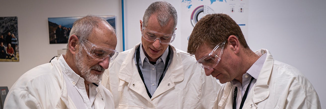 Three male PPG employees wearing PPE whilst discussing