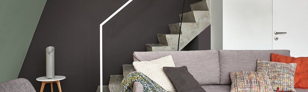 Een bank met kussens en een deken op de arm van een bank