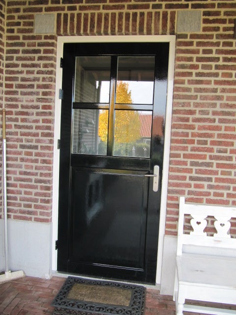 Een zwarte deur met glazen ruiten aan de zijkant van een bakstenen gebouw