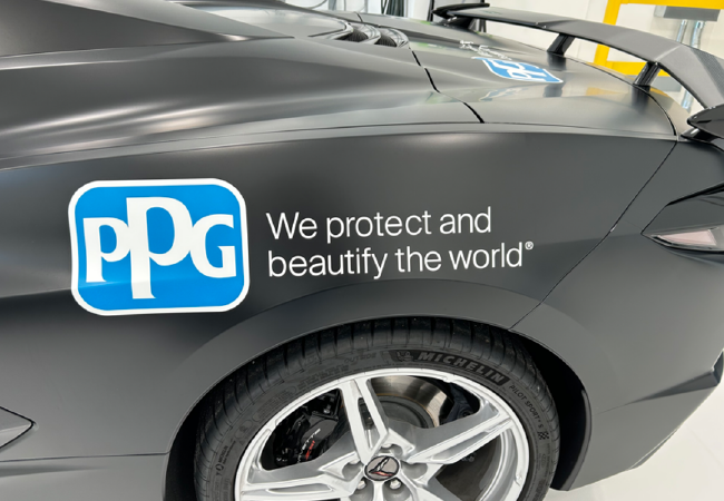 Close-up of a matte gray vehicle panel featuring a blue PPG logo and the slogan “We protect and beautify the world.”