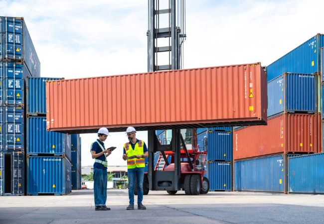Multicolored shipping containers at dock with two men in front