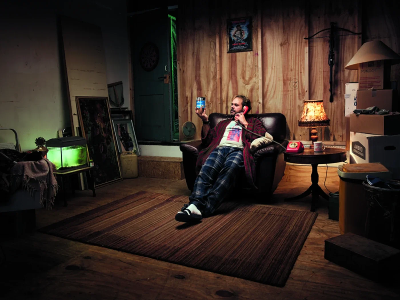 Man zit n een leren fauteuil in een houten mancave en houdt een telefoon vast