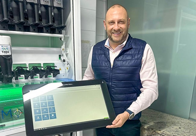 Julio Bueno, a PPG employee within our Automotive Refinish Coatings business, next to PPG MoonWalk paint mixing machine