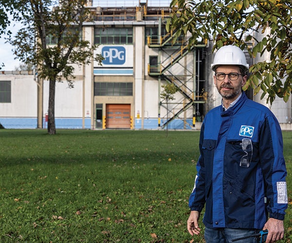Male PPG employee next to large PPG building and trees