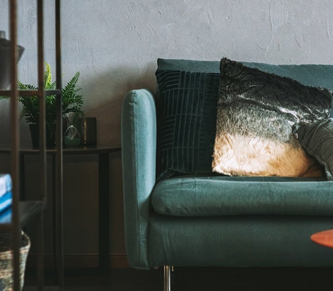 Zelený gauč s polštářem na něm