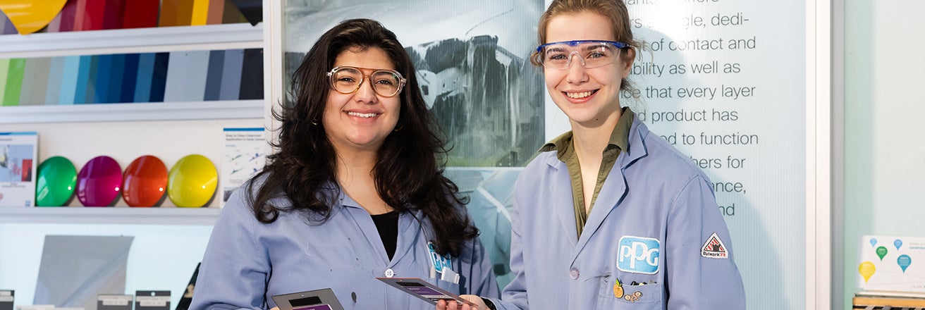 Two female colleagues wearing PPG overalls examining colour swatches