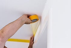 Iemand die een meetlint gebruikt om het plafond op te meten