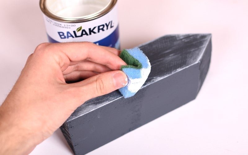 Ruka, která drží houbu nad černým blokem