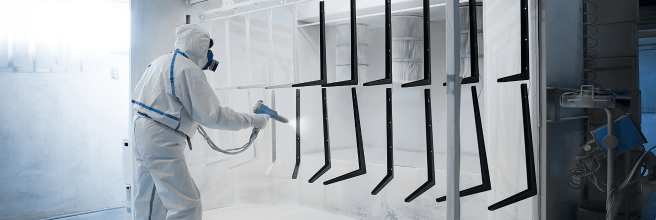 Man spraying metal parts with white powder coatings