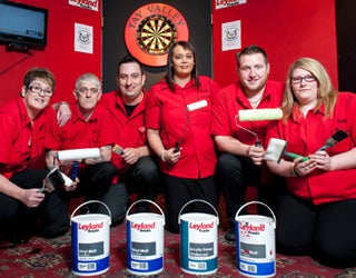 A group of Leyland workers posing for a picture with darts in the background.