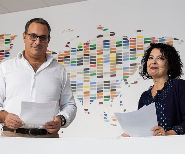 Two employees stood next to world map made of color swatches