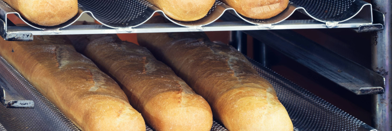 View to left of bread trays with perforated bases with baked baguettes