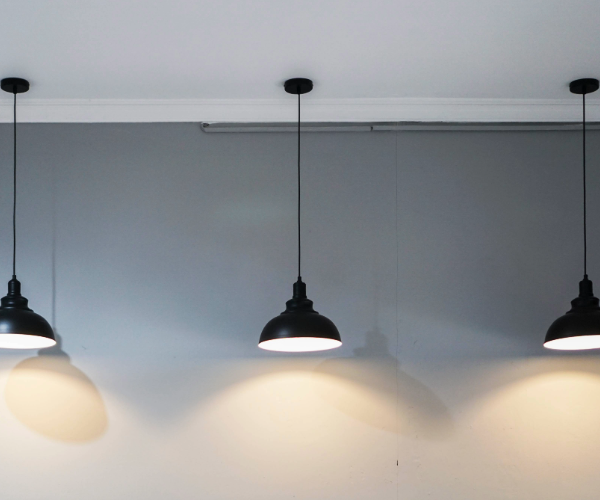 Three metal interior pendant lights against a wall 