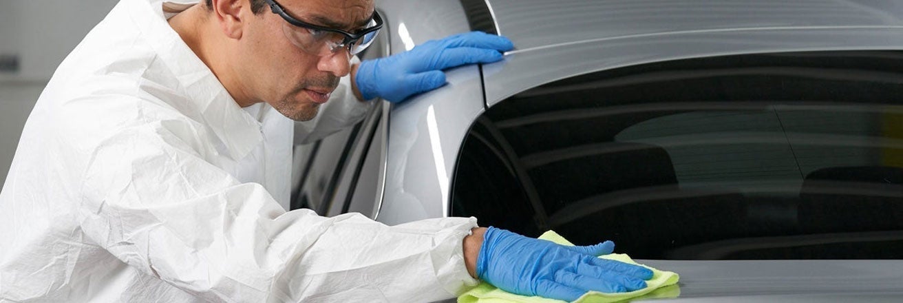 Man wearing PPE polishing car bodywork