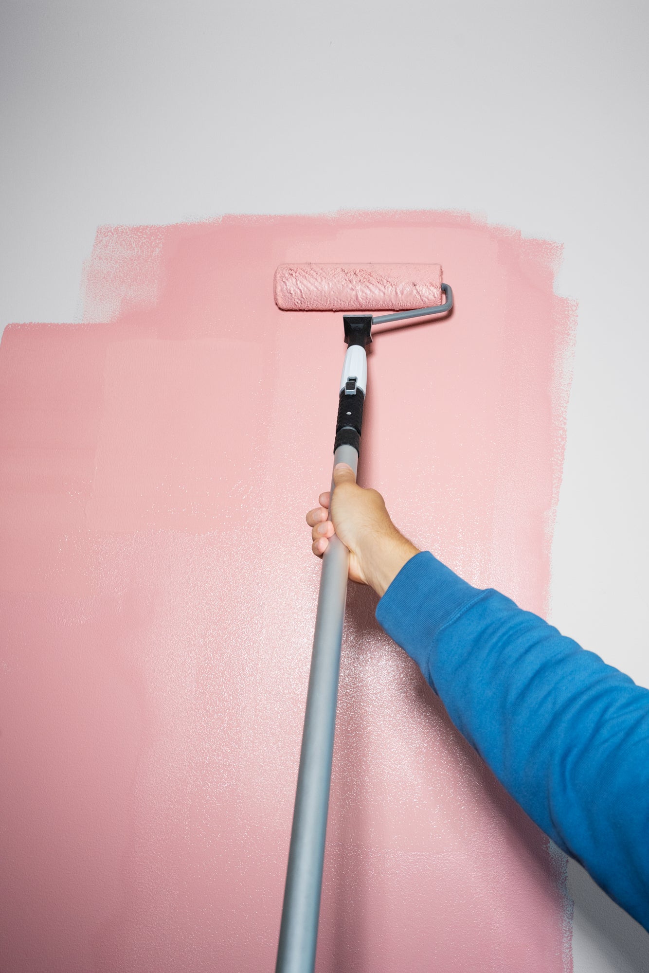 person holding a roller and painting a wall