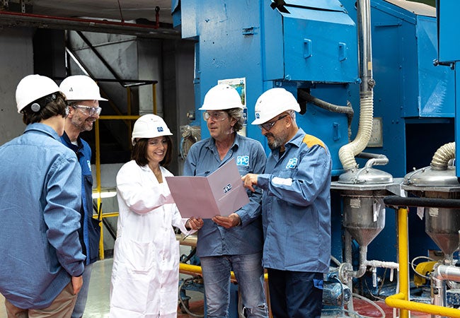 PPG workers in factory discussing information from handbook