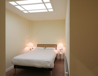 A bed in a room with a skylight insde a hotel.