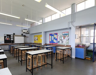 Room with tables and stools arranged classroom-style.