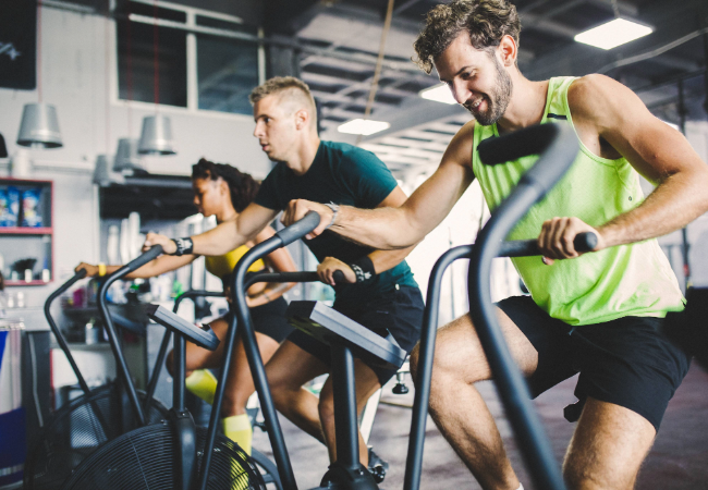 Men and woman riding exercise bikes in group workout class