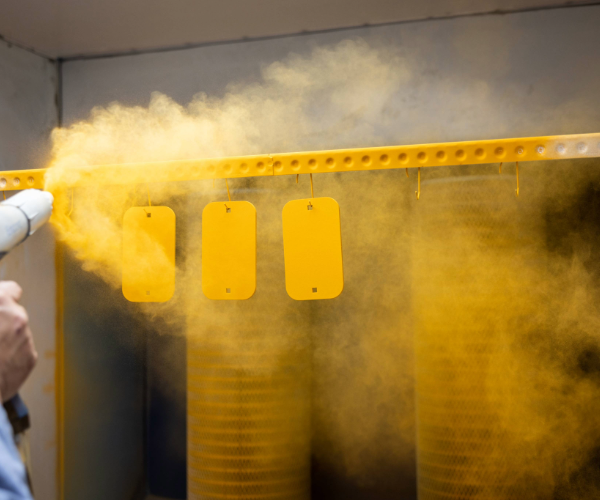 Parts being sprayed with yellow powder coating