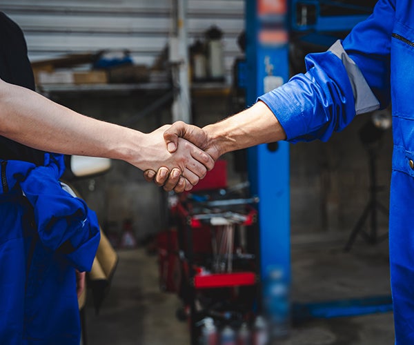 Two workers shaking hands in workshop