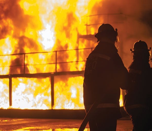 A firefighter standing in front of a large fire