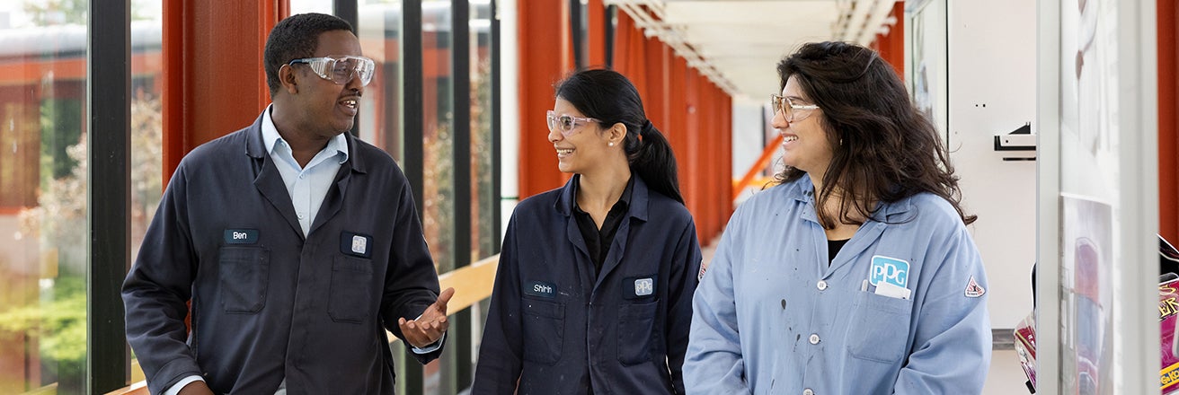 Group of male and female colleagues walking and discussing whilst wearing PPG jackets