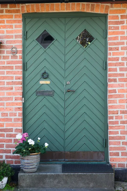Grönmålad ytterdörr till tegelfasad