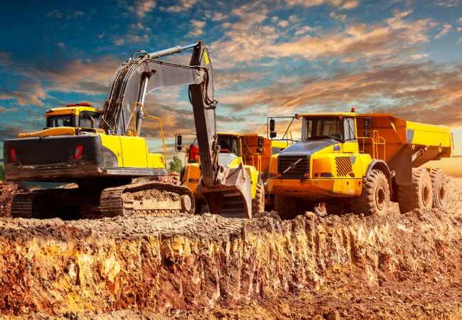 Two yellow construction equipment vehicles outdoors moving dirt