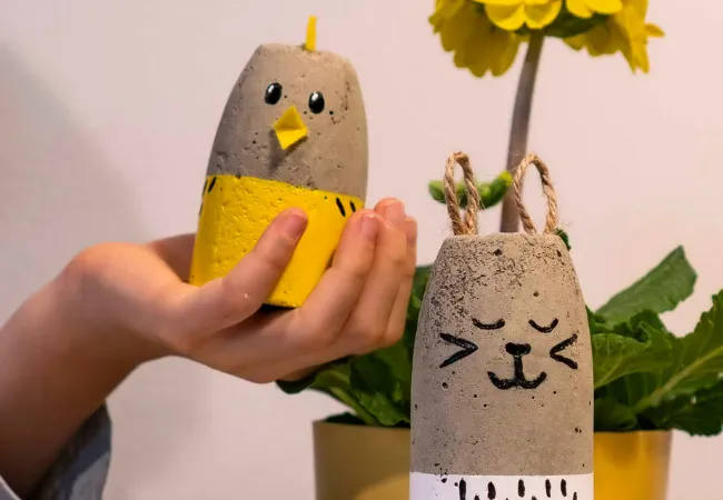 Ruka, která drží kamenného ptáka a kočku