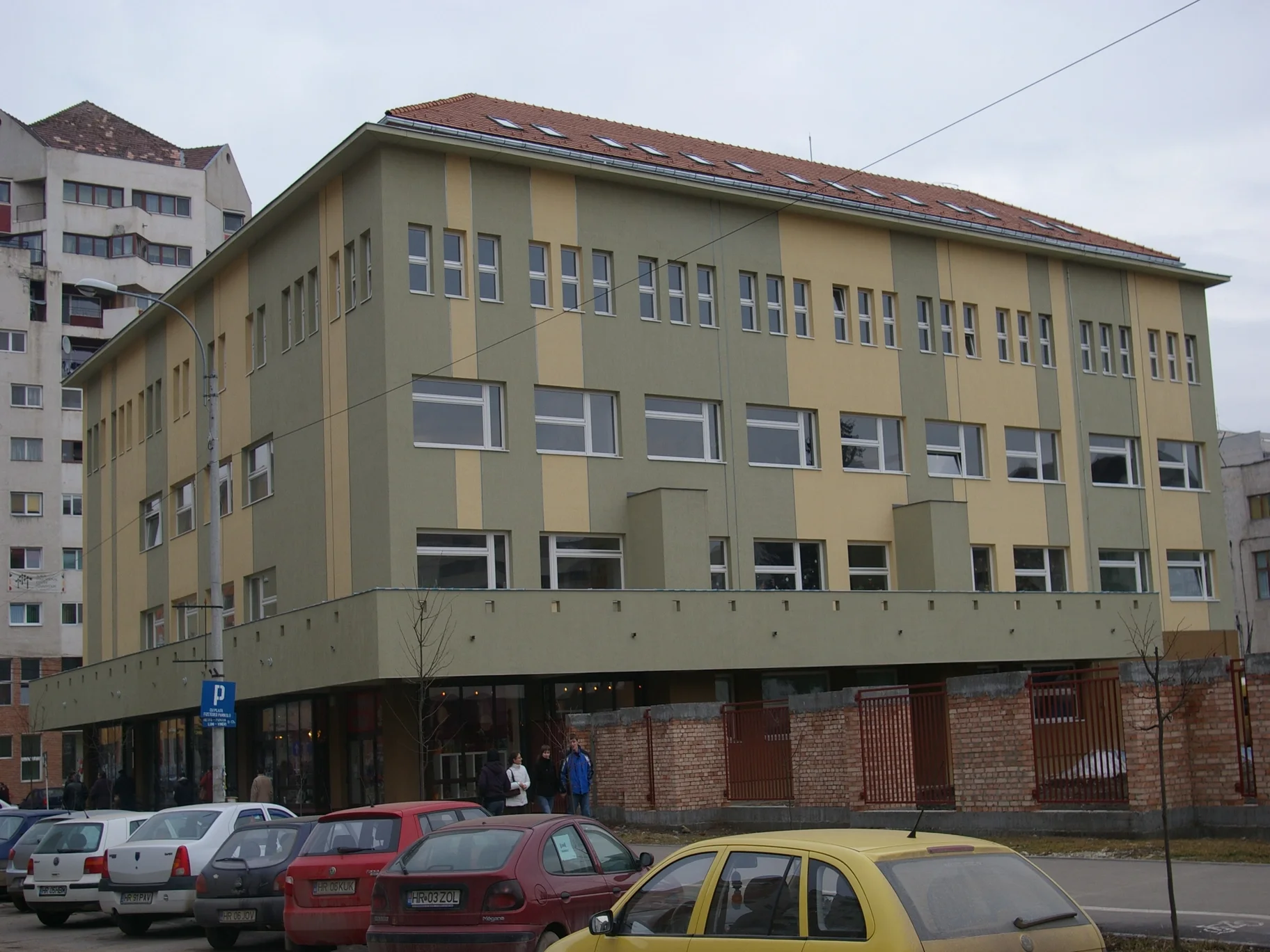 O clădire cu multe mașini parcate în fața ei