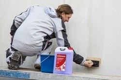 Muž používá základní nátěr na zeď