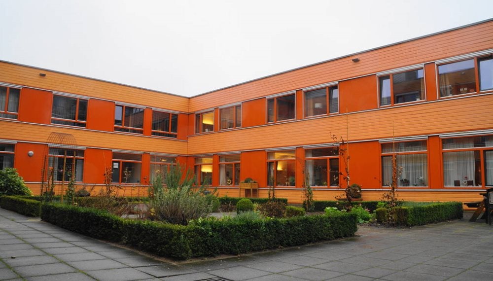 Een oranje gebouw met een tuin