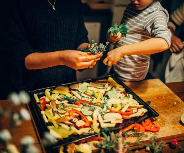 Adult and child preparing mixed vegetables in baking tray