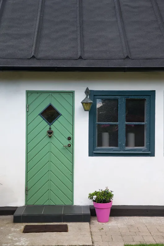 Grönmålad ytterdörr till vit fasad